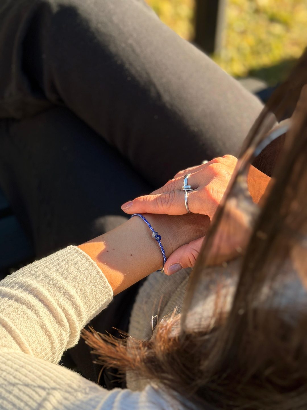 AURA Natural — Pulsera y anillos junto a un pañuelo, luz de atardecer