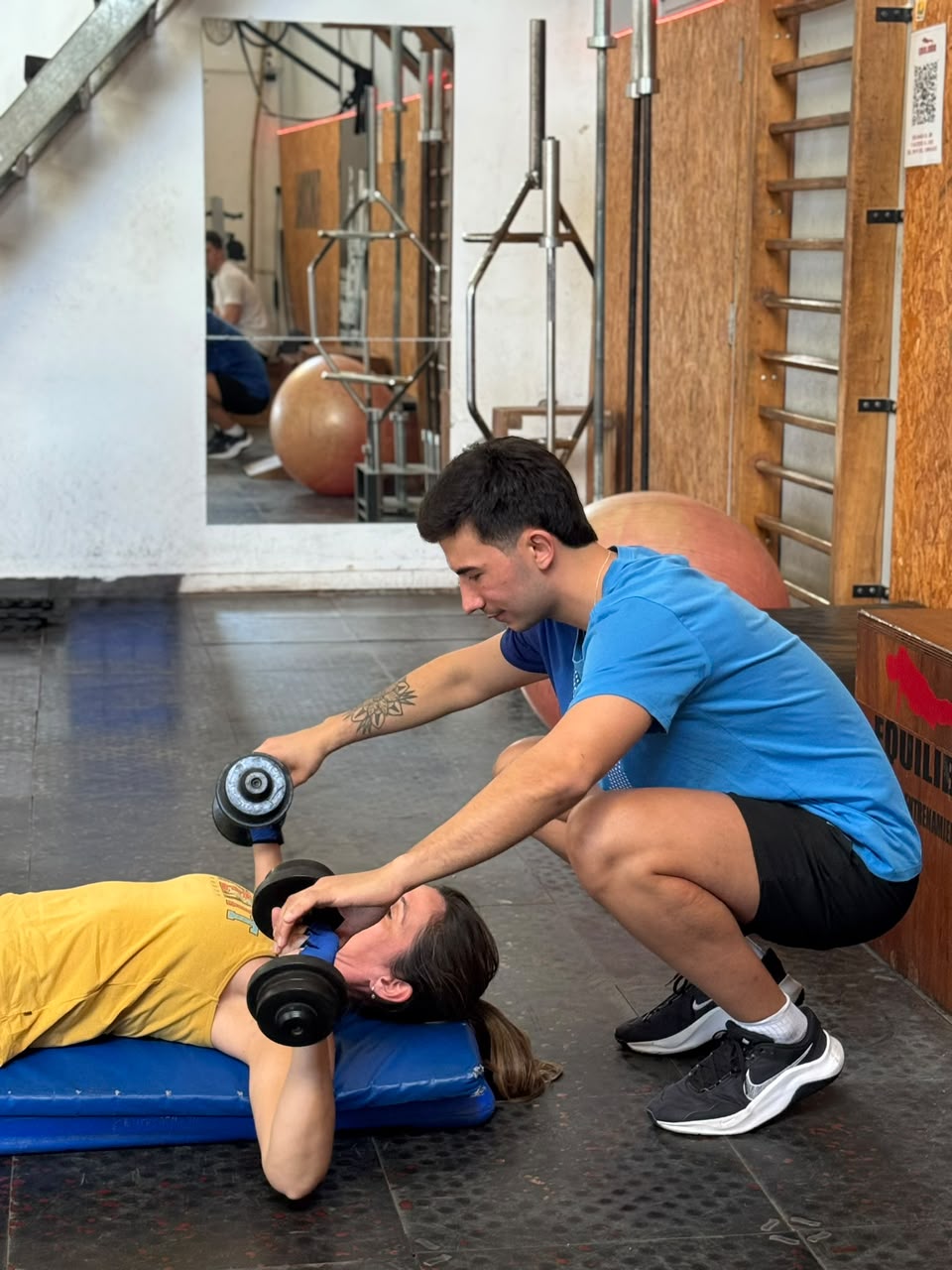 Equilibrio Gimnasio — Entrenador asistiendo un ejercicio con mancuerna